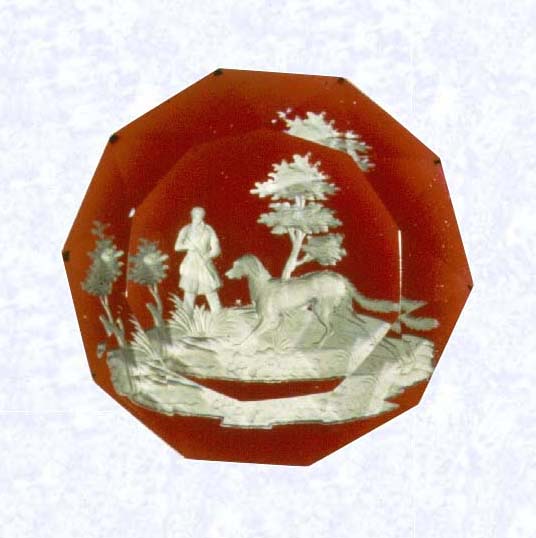 <B>Sulphide Hunter and Dog<BR>France<BR>Baccarat, circa 1845-55</B><BR>Diameter: 8.2 cm (3 1/4 inches)<BR>(702254)<BR><BR>Sulphide scene of a hunter and dog; set on a translucent red footed base; sides cut with triangular facets; ten-sided facet cut on top