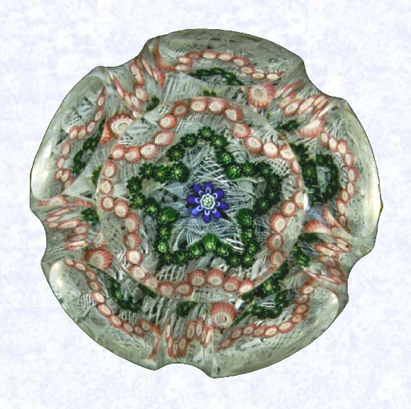<B>Fluted Garland Millefiori<BR>France<BR>Clichy, circa 1845-55</B><BR>Diameter: 7 cm (2 3/4 inches)<BR>(702308)<BR><BR>Garland millefiori with one green and one pink cinquefoil garland, around a blue center cane; on a white filigree ground backed with parallel lengths of white filigree twists; sides cut with five circular printies separated by five vertically cut flutes; circular printy cut on top; (formerly in the collection of King Farouk of Egypt)