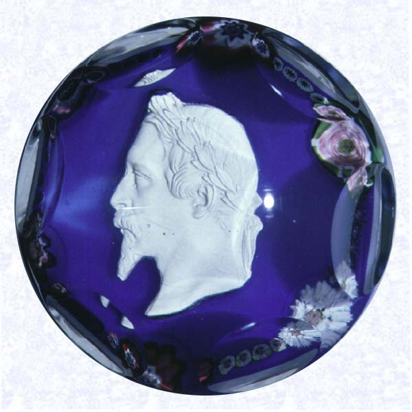<B>Napoleon III Sulphide Portrait on Blue<BR>France<BR>Clichy, circa 1845-55</B><BR>Diameter: 7.6 cm (3 inches(<BR>(702329)<BR><BR>Sulphide profile portrait of Louis Napoleon Bonaparte (Napoleon III); encircled by a ring of mulitcolored florets, including one pink clichy rose; set on an opaque white ground overlaid with blue; sides cut with six circular printies