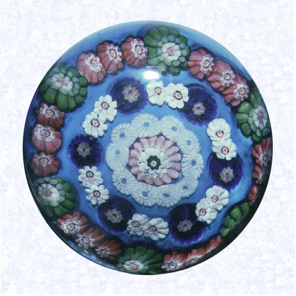 <B>Spaced Concentric Millefiori on Blue<BR>France<BR>Clichy, circa 1845-55</B><BR>Diameter: 7.6 cm (3 inches)<BR>(702382)<BR><BR>Spaced concentric millefiori with three spaced rings; outer ring with alternating pink and green canes, middle ring with alternating dark blue and white canes, inner ring of white canes; around a pink and white center cane; on a light blue opaque ground