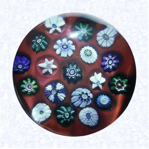 <B>Spaced Millefiori on Dark Red<BR>France<BR>Clichy, circa 1845-55</B><BR>Diameter: 6.5 cm (2 1/2 inches)<BR>(702456)<BR><BR>Spaced millefiori canes in white, green, purple, and blue; set in a dark red-over-opaque ground; diamond-cut base