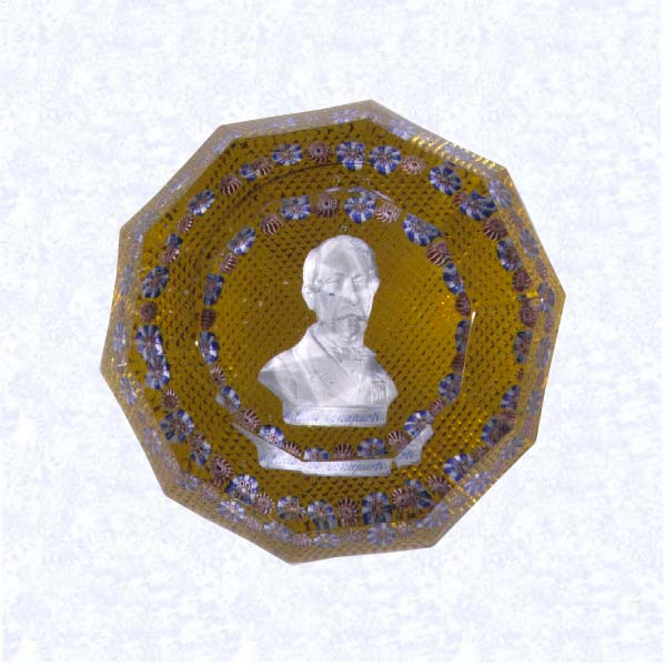 <B>Sulphide Portrait of Napoleon III on Amber<BR>France<BR>Saint Louis, circa 1845-55</B><BR>Diameter: 8.2 cm (3 1/4 inches)<BR>(702476)<BR><BR>Sulphide portrait of Louis Napoleon Bonaparte; &quotd louis bonaparte" inscribed on plinth; encircled by a ring of alternating blue and pink millefiori canes; amber-flashed, diamond-cut base; sides cut with three rows of four-sided printies; top cut with a ten-sided printy