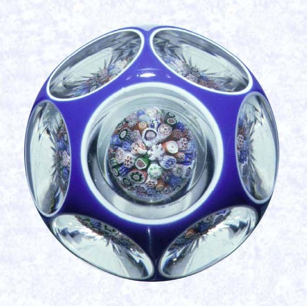 <B>Double Overlay with Mushroom<BR>France<BR> Baccarat, circa 1845-55</B><BR>Diameter: 8.2 cm 3 1/4 inches)<BR>(702248)<BR><BR>Double overlay (opaque white overlaid with dark blue), enclosing a close concentric millefiori mushroom; star-cut base; sides cut with six circular printies, one on top