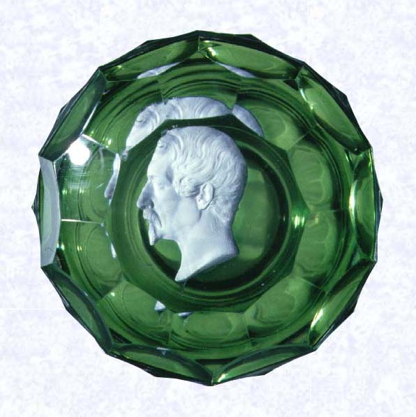 <B>Louis Napoleon Bonaparte<BR>France<BR>Baccarat, circa 1845-55</B><BR>Diameter: 8.2 cm (3 1/4 inches)<BR>(702250)<BR><BR>Sulphide portrait of Louis Napoleon Bonaparte (Napoleon III); set on a translucent emerald green footed base; sides cut with three rows of honeycomb printies; ten-sided printy cut on top