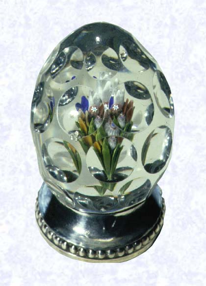 <B>Lampworked Handcooler<BR>France<BR>Saint Louis, circa 1845-55</B><BR>Diameter: 4.5 cm (1 3/4 inches, Height: 7 cm (2 3/4 inches<BR>(702256)<BR><BR>Lampworked upright bouquet in an egg-shaped handcooler; sides cut with four rows of circular printies; circular sterling silver base