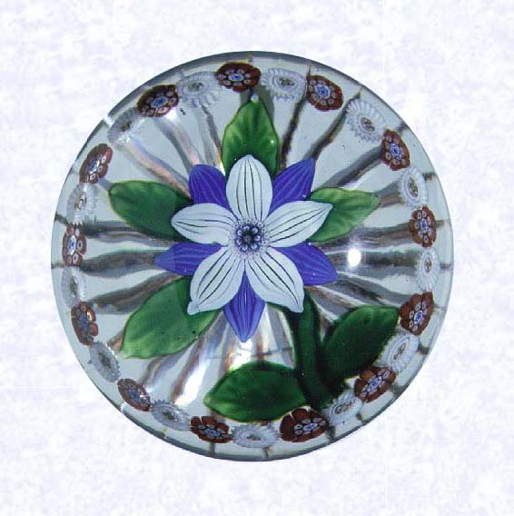 <B>Lampworked Blue and White Clematis<BR>France<BR>Baccarat, circa 1845-55</B><BR>Diameter: 6.5 cm (2 1/2 inches)<BR>(702270)<BR><BR>Lampworked deep blue and white clematis blossom with a red, white, and blue center cane; six green leaves and stem; encircled by a ring of alternating red and white millefiori canes; star-cut base