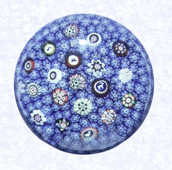 <B>Spaced Millefiori on Carpet Ground<BR>France<BR>Baccarat (signed), dated 1848</B><BR>Diameter: 7.3 cm (2 7/8 inches)<BR>(702299)<BR><BR>Carpet ground of blue and white star and rod canes; inset with spaced millefiori canes, including five silhouettes and one signed and dated cane inscribed &quotB/1848"