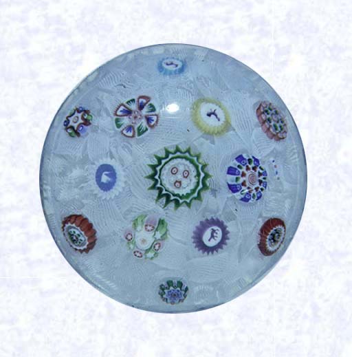 <B>Spaced Millefiori on Filigree<BR>France<BR>Baccarat, dated 1849</B><BR>Diameter: 6 cm (2 3/8 inches)<BR>(702310)<BR><BR>Spaced millefiori canes, including five silhouette canes and one dated cane inscribed " 1849;" on a white filigree ground