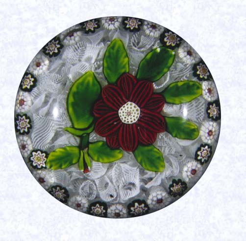 <B>Lampworked Red Clematis on Filigree<BR>France<BR>Baccarat, circa 1845-55</B><BR>Diameter: 7 cm (2 3/4 inches)<BR>(702311)<BR><BR>Lampworked red clematis with a red bud; white center cane; eight green leaves and stem; encircled by a ring of alternating green and white millefiori canes; on a white filigree ground