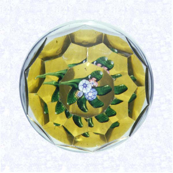 <B>Lampworked Posy Miniature<BR>France<BR>Saint Louis, circa 1845-55</B><BR>Diameter: 5.1 cm (2 inches)<BR>(702346)<BR><BR>Miniature weight with a flat posy of white, pink, blue, and yellow millefiori cane flowers; five green lampworked leaves; amber-flashed base; sides cut with four rows of hexagonal printies; ten-sided printy cut on top