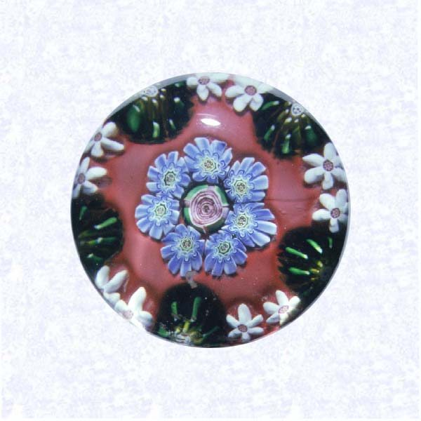 <B>Miniature Pattern Millefiori on Red<BR>France<BR>Clichy, circa 1845-55</B><BR>Diameter: 4.2 cm (1 5/8 inches)<BR>(702362)<BR><BR>Miniature pattern millefiori with concentric rings of millefiori canes in green, white, and blue, around a central pink Clichy rose; on an opaque red ground