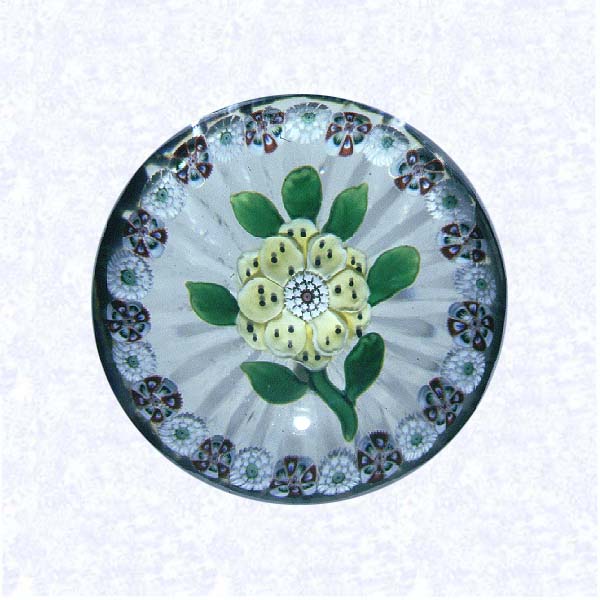 <B>Lampworked Wheat Flower with Millefiori Ring<BR>France<BR>Baccarat, circa 1845-55</B><BR>Diameter: 6 cm (2 3/8 inches)<BR>(702371)<BR><BR>Pale yellow lampworked wheat flower blossom with black dots on petals; white and red center cane; seven green leaves and stem; encircled by a ring of alternating red and white millefiori canes; star-cut base