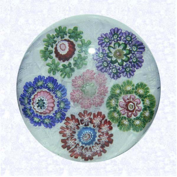 <B>Garland MIllefiori on Filigree<BR>France<BR>Clichy, circa 1845-55</B><BR>Diameter: 7 cm (2 3/4 inches)<BR>(702387)<BR><BR>Garland millefiori with five circlets in blue, green, purple, and red canes, each containing a single center cane, encircling a central pink circlet with a green center cane; on a white filigree ground backed with parallel lengths of white filigree twists