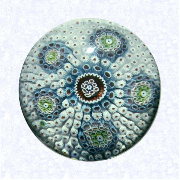 <B>Carpet Ground Millefiori<BR>France <BR>Saint Louis, circa 1845-55</B><BR>Diameter: 6.5 cm (2 1/2 inches)<BR>(702412)<BR><BR>Carpet ground of red star-centered, white cog canes; inset with five circular groupings of light blue, pink, green, and white canes; around a central floret in red and white