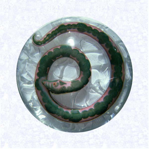 <B>Pink Lampworked Snake on Filigree<BR>France<BR>Baccarat (attributed), circa 1845-55</B><BR>Diameter: 7.6 cm (3 inches)<BR>(702423)<BR><BR>Pink lampworked snake with green mottling; red eye with black pupil; coiled on a white filigree ground; single bubble flanks head, one between coils