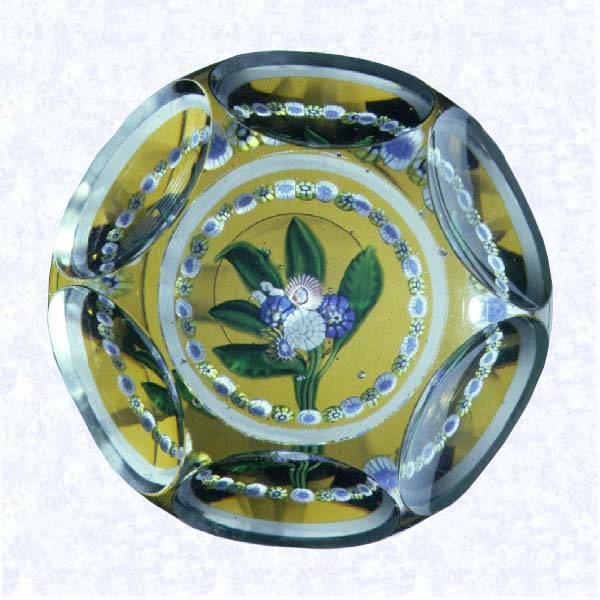 <B>Flat Posy on Amber<BR>France<BR>Saint Louis, circa 1845-55</B><BR>Diameter: 8 cm (3 1/8 inches)<BR>(702446)<BR><BR>Flat posy of blue, pink, white, and yellow millefiori cane flowers with five green lampworked leaves; encircled by a ring of alternating yellow and white millefiori canes; amber-flashed base; sides cut with six circular printies, one on top