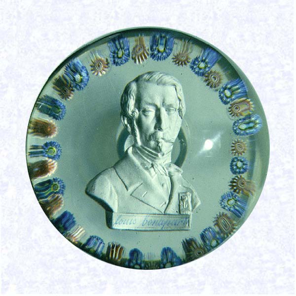 <B>Sulphide Portrait of Napoleon III<BR>France<BR>Saint Louis, circa 1845-55</B><BR>Diameter: 7.6 cm (3 inches)<BR>(702475)<BR><BR>Sulphide portrait of Louis Napoleon Bonaparte; " d louis bonaparte" inscribed on plinth; encircled by a ring of alternating blue and pink millefiori canes